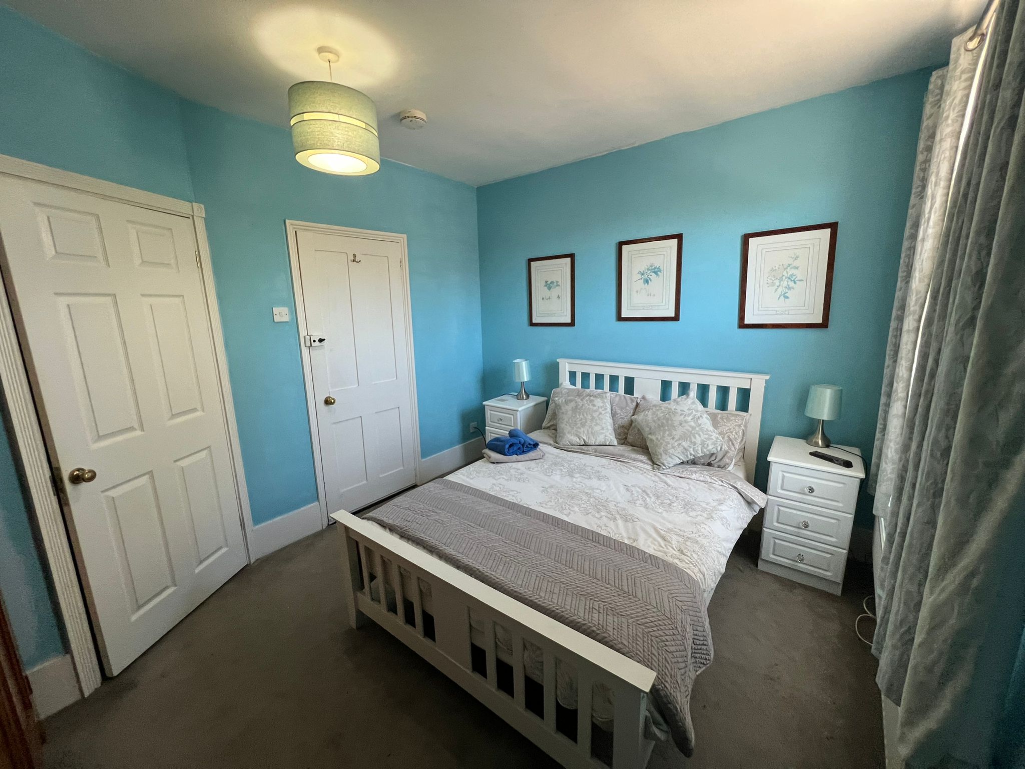 Double Room — white bed with botanical prints on blue walls
